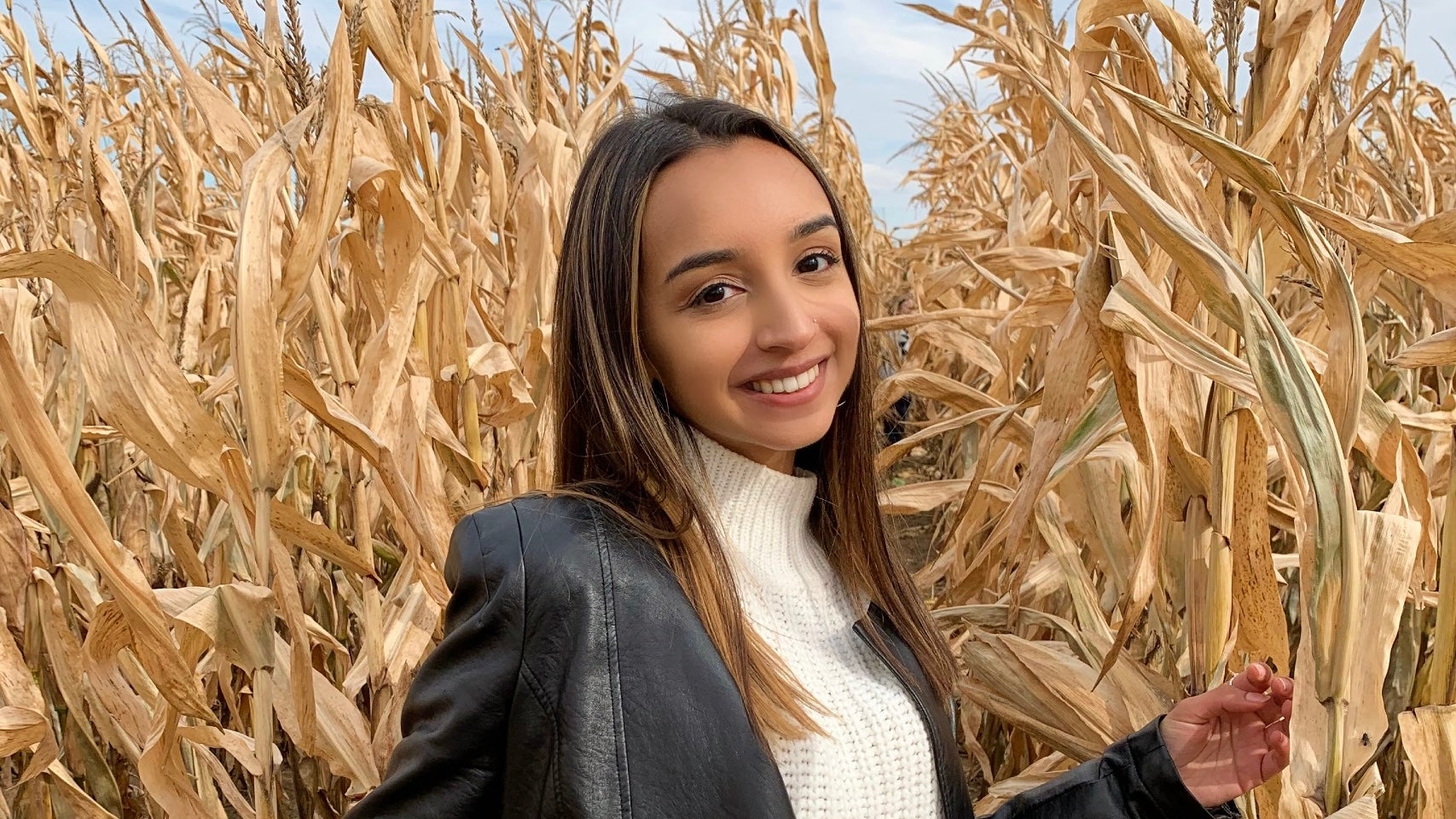 A photo of Sarina smiling in a corn field.