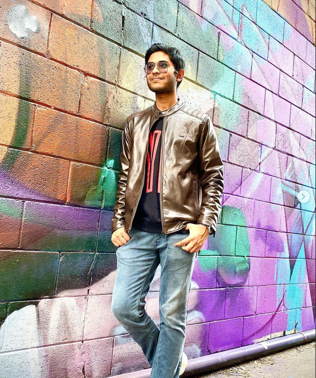 Arnav leaning against a colourful wall.