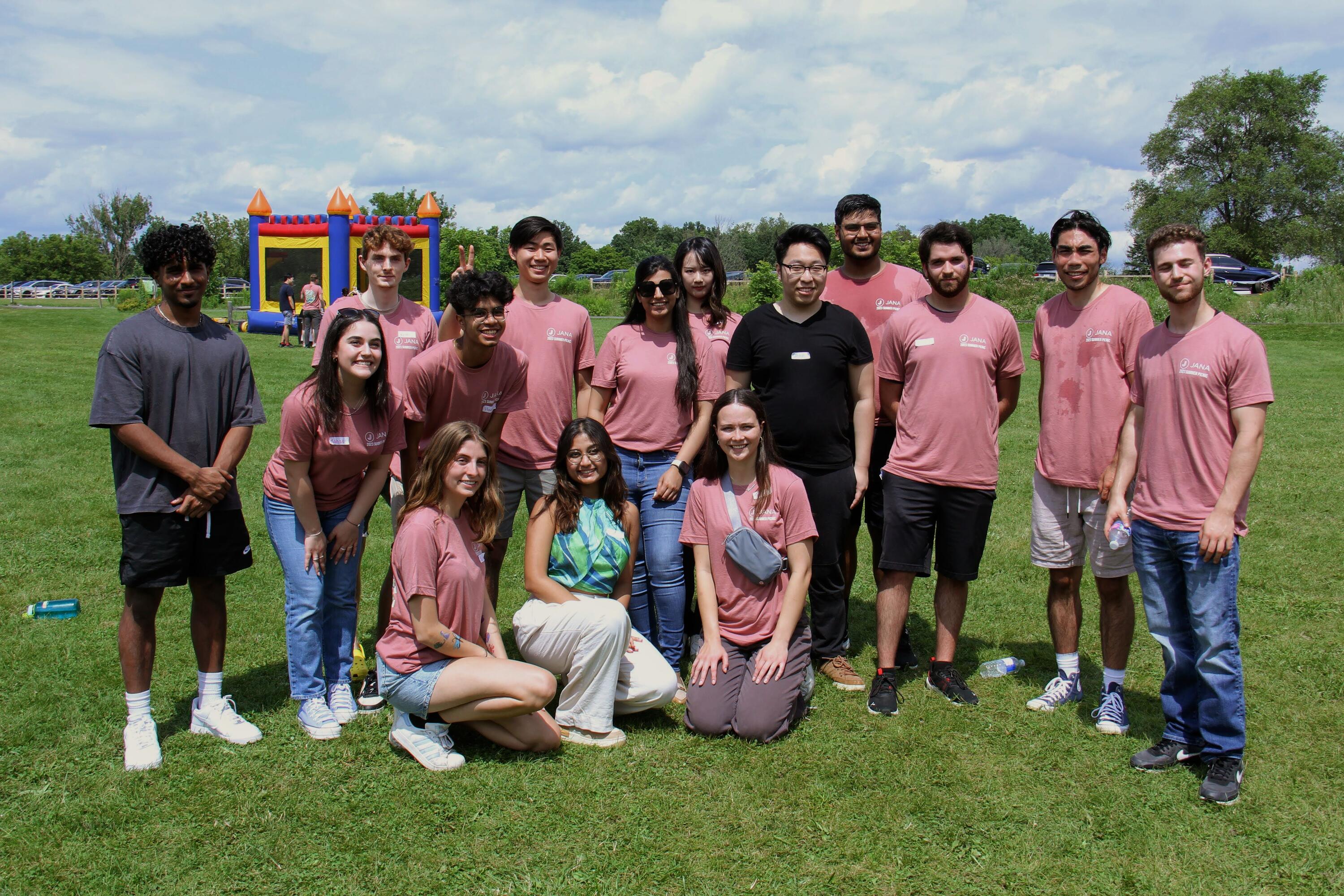 Shashwat and the team at JANA posing in a soccer field with a bouncy castle in the distance. 