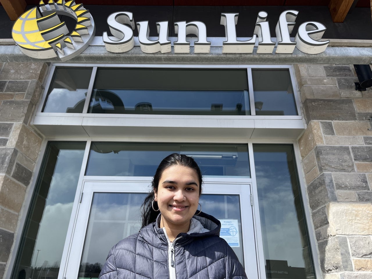 A photo of Sanooba standing in front of the Sun Life Financial building.