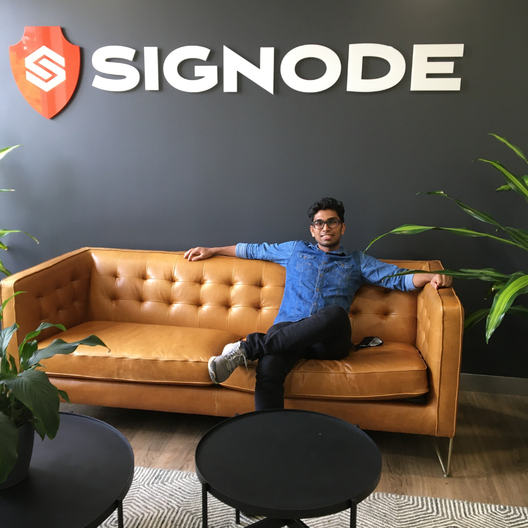 Saurav in front of a Signode sign sitting on a couch