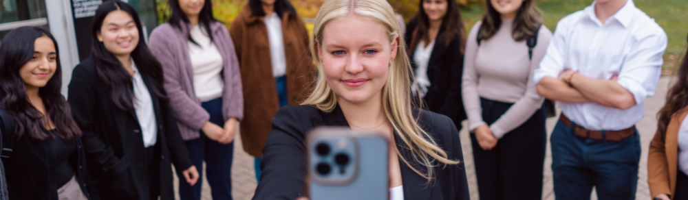 Student holding their phone smiling into the camera