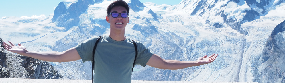 Photo of andrew ding in switzerland on his international co-op work term.He is standing in front of snow capped mountains.
