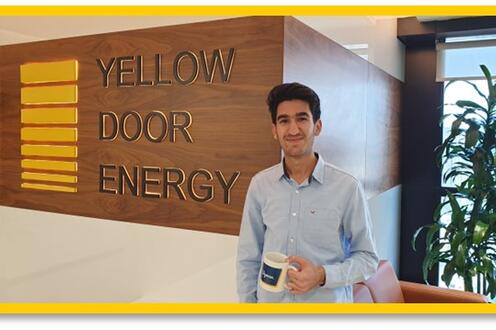 Ayman Gostar smiling in front of Yellow Door Energy wall