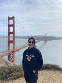 A picture of Yuvika standing in front of the Golden Gate Bridge, wearing a UWaterloo Shirt.