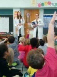 Pharmacy students talking to a class full with children.