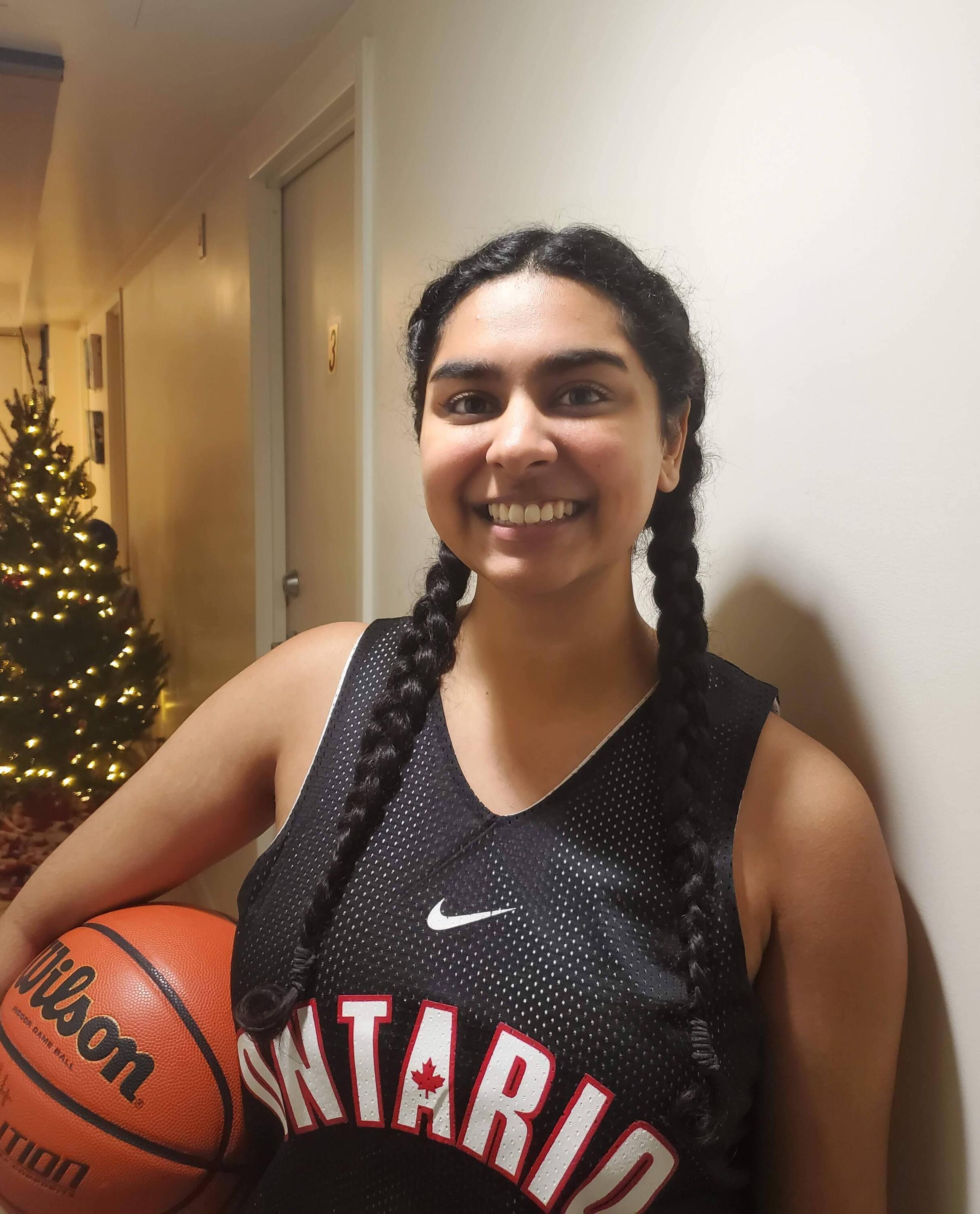 Natalie Fernandez wearing a jersey and holding a basketball