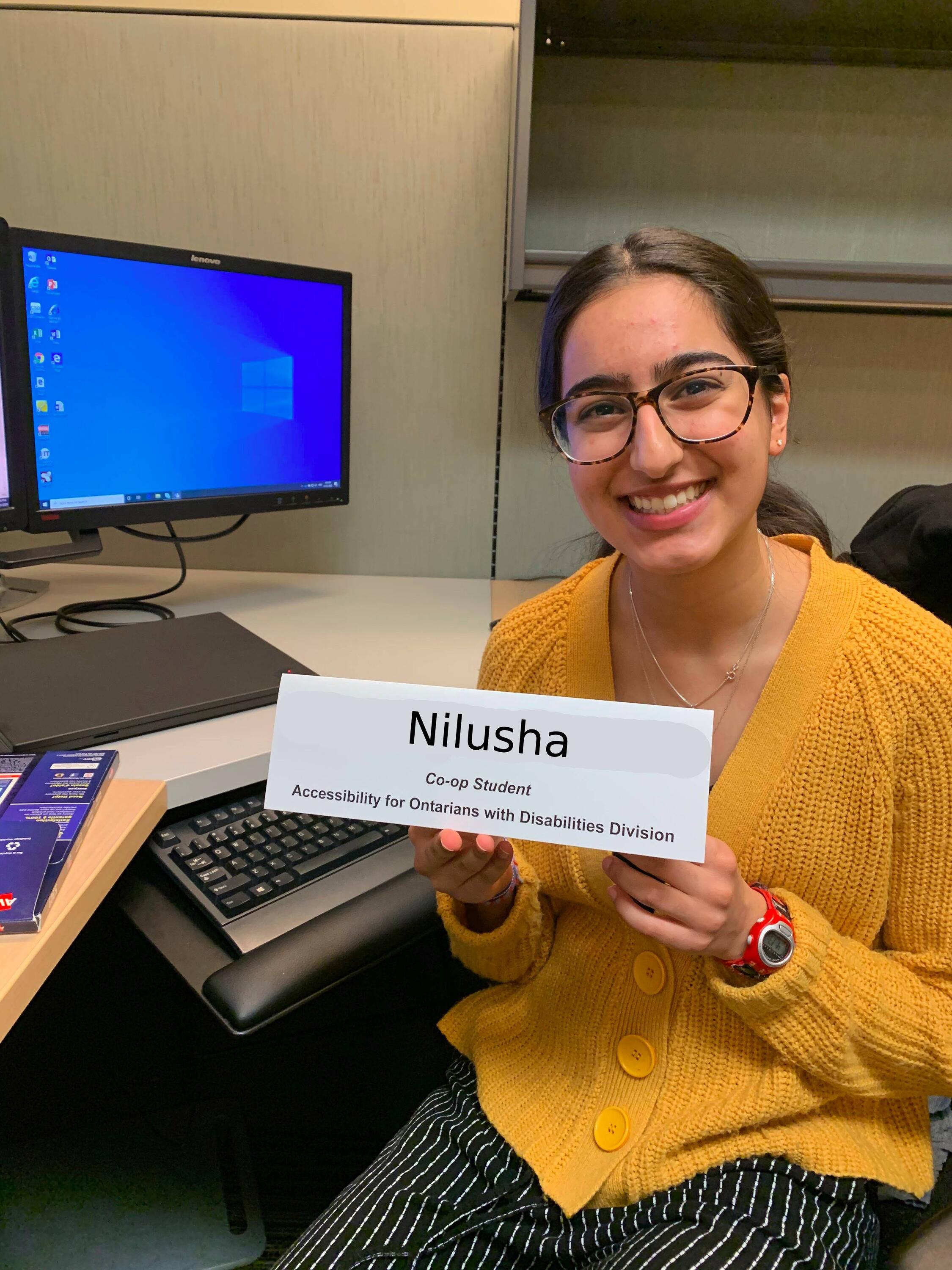 Nilusha smiling with her name tag at work