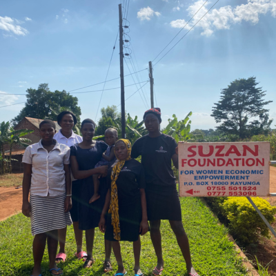 Women and children standing next to a Suzan Foundation sign
