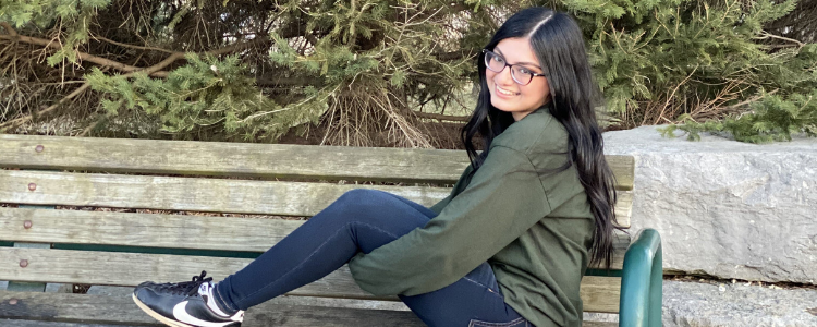 University of Waterloo Engineering co-op student, Sana Allana, sitting on a park bench and smiling.