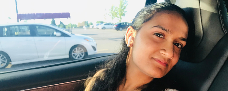 University of Waterloo Health co-op student, Navya Manoj, sitting in a car and smiling.