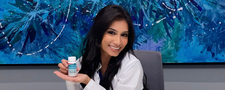 University of Waterloo Science co-op student, Esha Awan, sitting on a chair and smiling, holding a pharmaceutical bottle. 