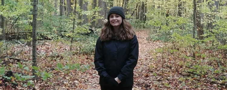 University of Waterloo Arts and Business co-op alum, Daynica Fisher, standing and smiling in a forest