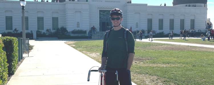 University of Waterloo student, Sam Roberge-Arnott, standing outside of Griffith Observatory with his bicycle.