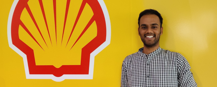 Narayanan (Nana) Ramakrishnan standing in front of a yellow wall, with a Shell Canada logo smiling.