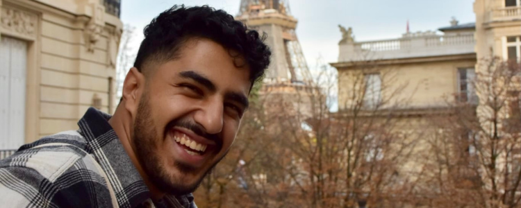 University of Wateroo student, Michael Salib, smiling in front of the Eiffel Tower.