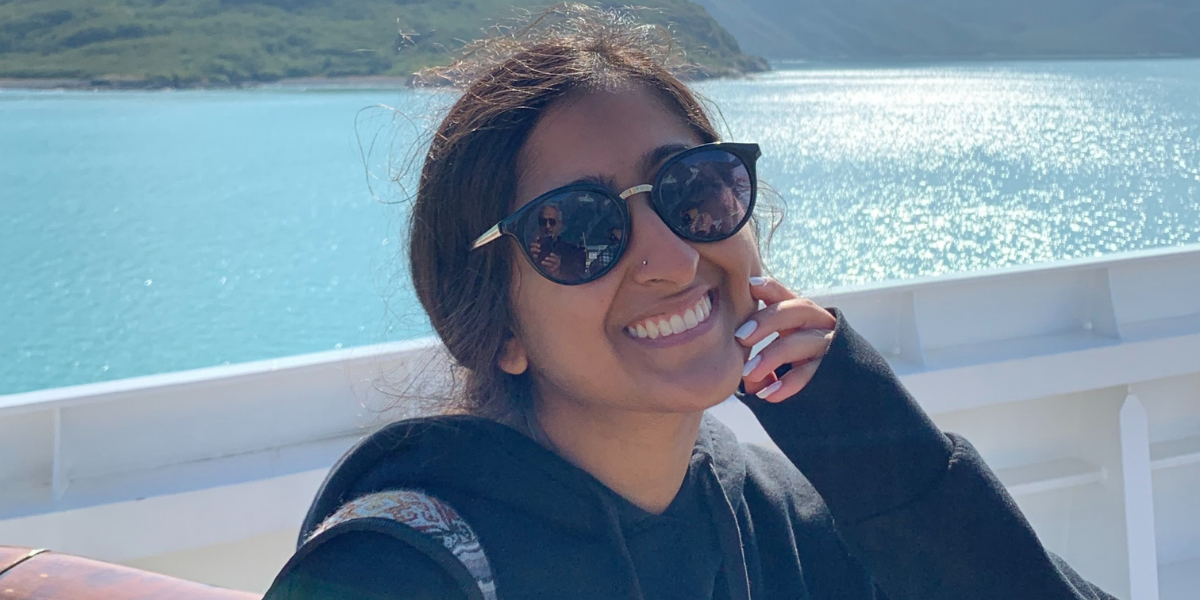 Celina wearing sunglasses and smiling in front of a lake
