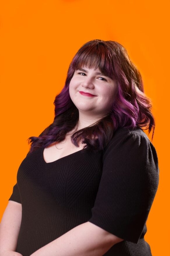 Stephanie Davis smiling headshot in front of an orange background