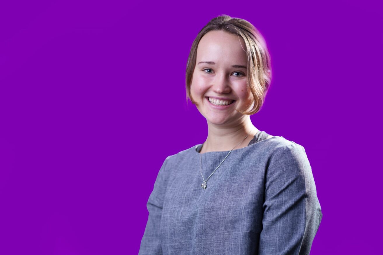 Frances Hallen smiling in front of a purple background