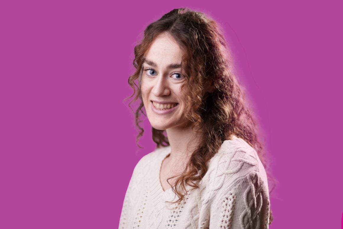 Jessica Bohm smiling in front of a pink colour background