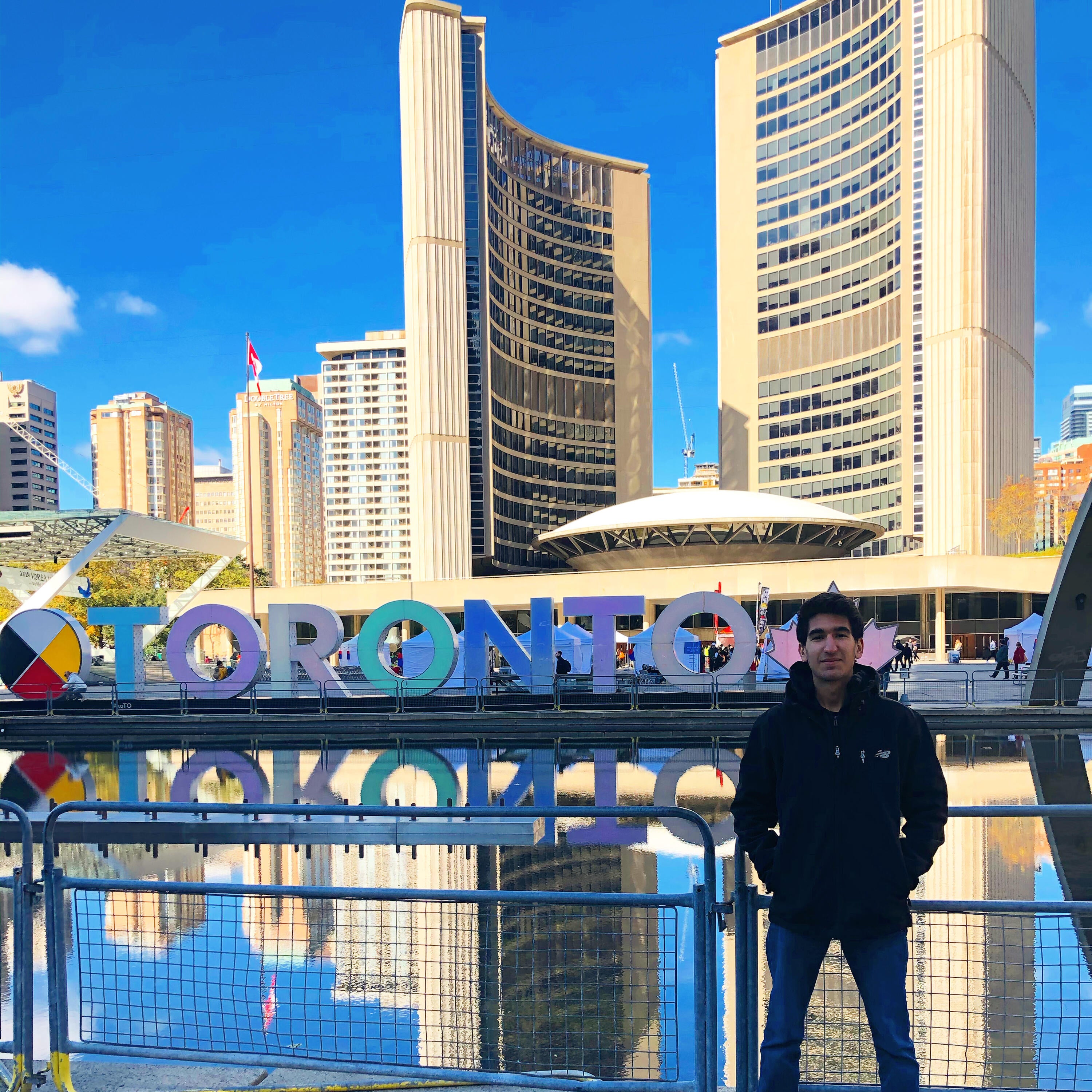 Ayman smiling with the Toronto sign outside in Downtown