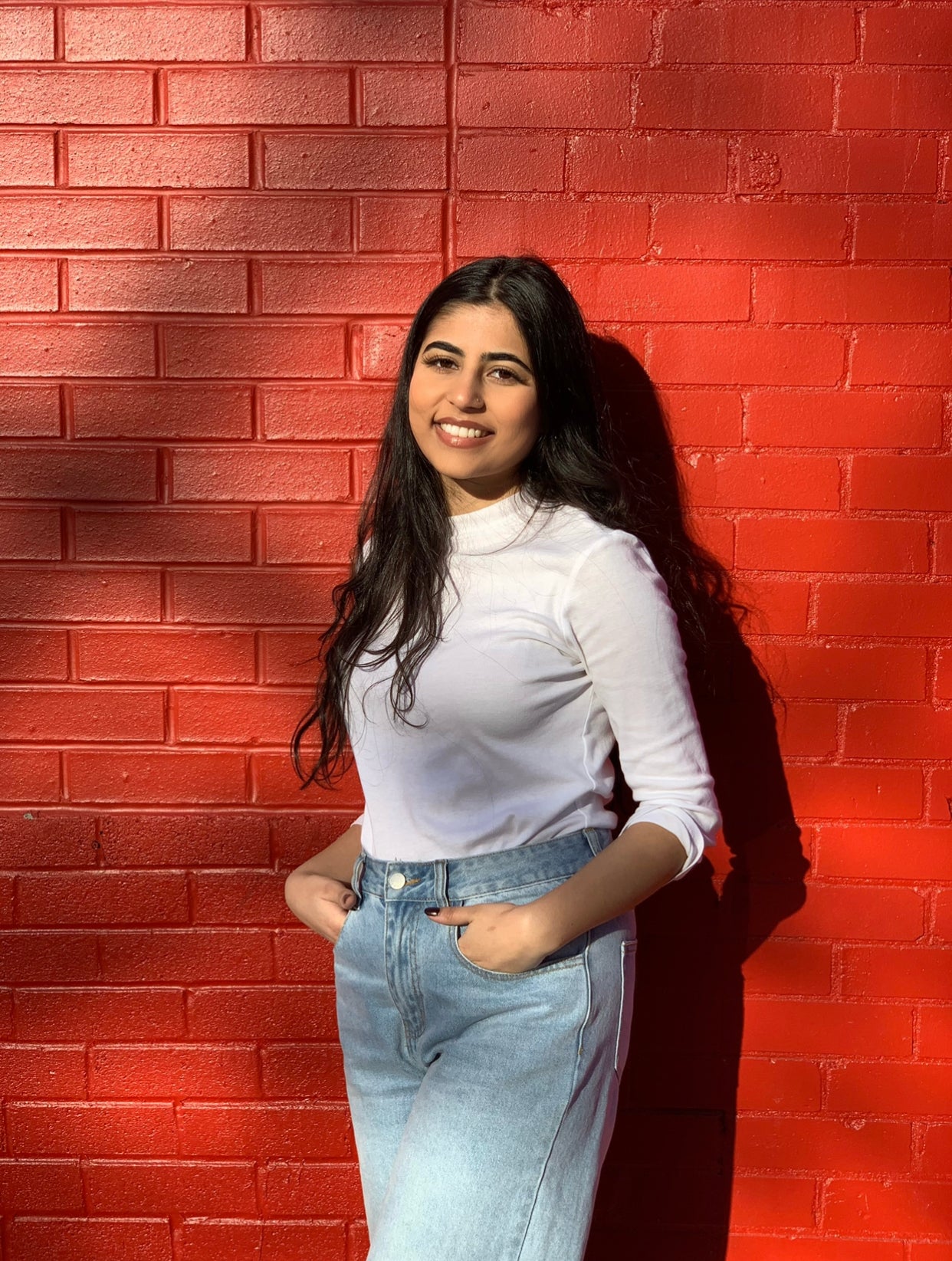Fatima smiling in front of a red wall
