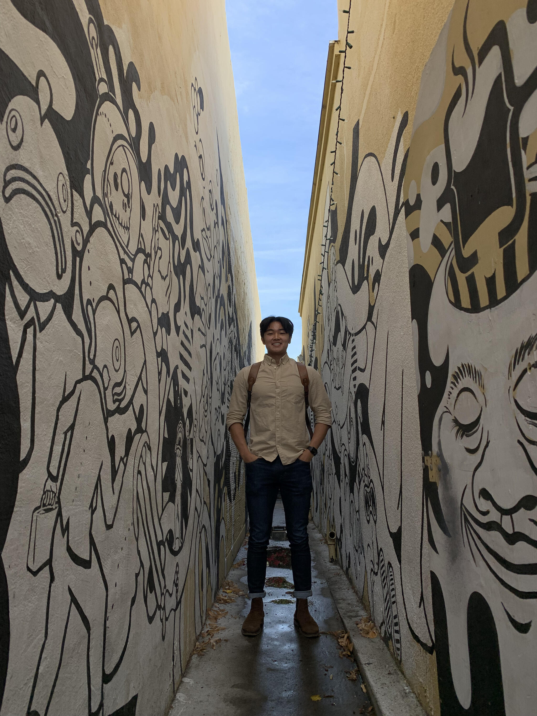 Photo of Jonny smiling and standing in a narrow alley.