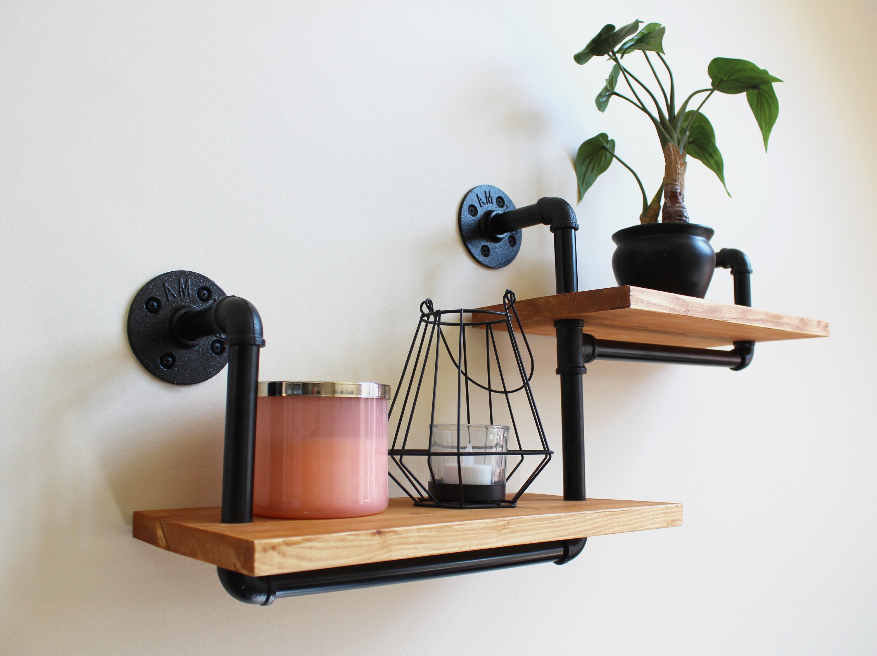 Photo of two wooden wall stands, with candles and a plant on them. The products which are sold by Madison's business. 
