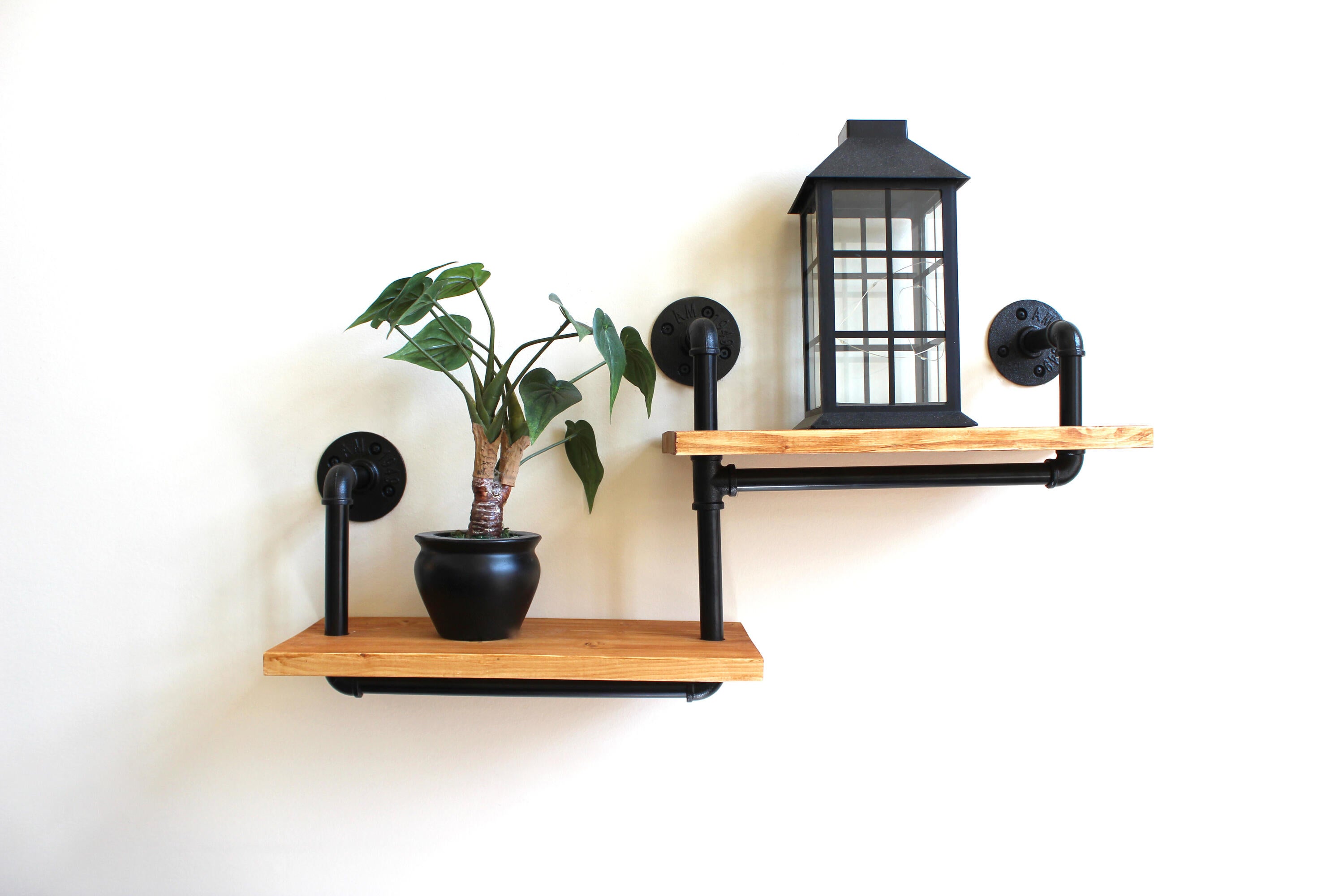Photo of two wooden wall stands. One with a plant on it, and the second one with a lantern on it.