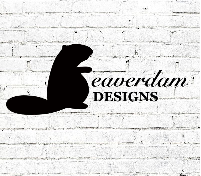Madison's business logo, which has a silhouette of a beaver and the title &quot;Beaverdam Designs&quot;, on a white brick wall.