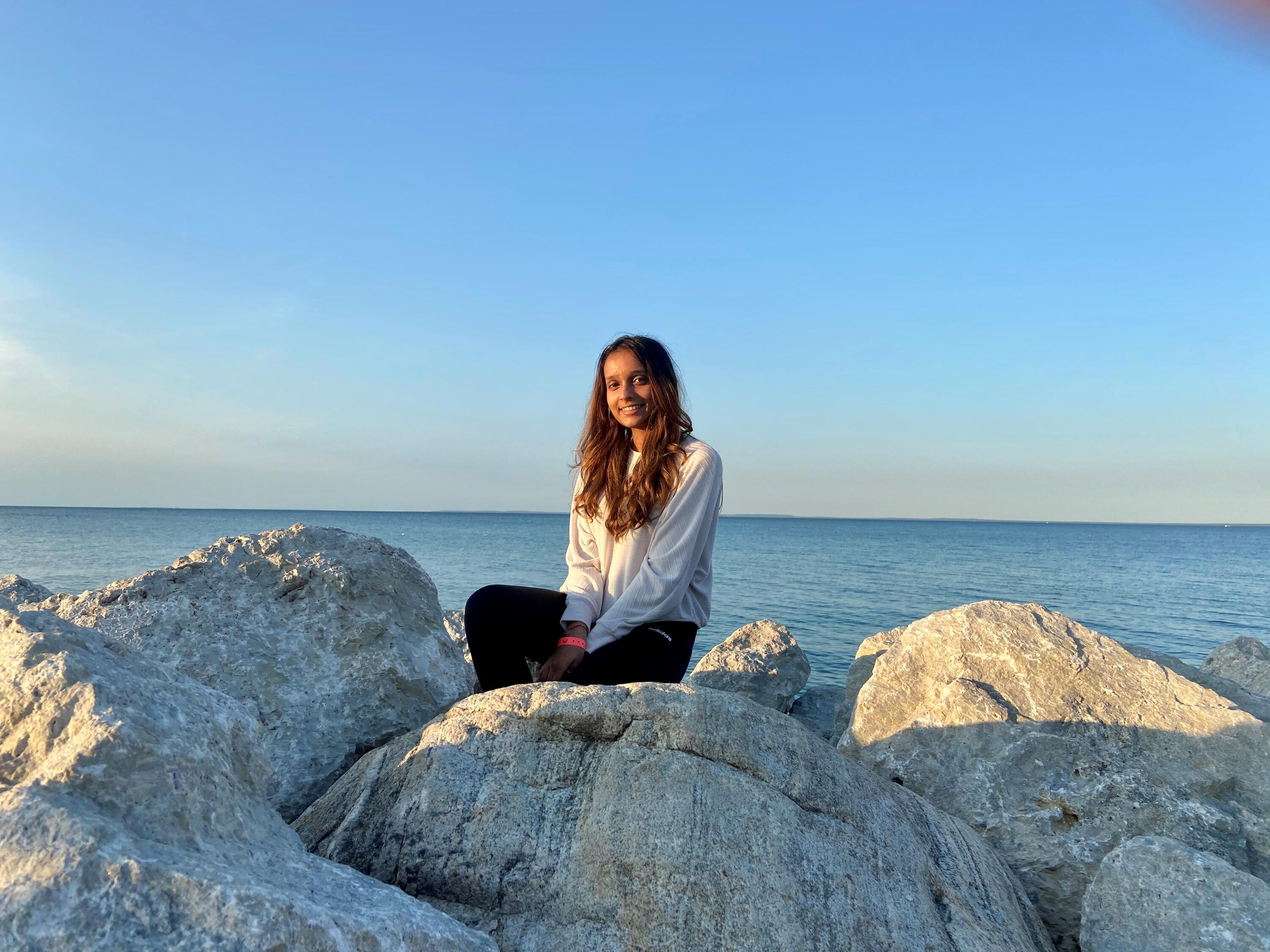Charita sitting on a rock at a beach