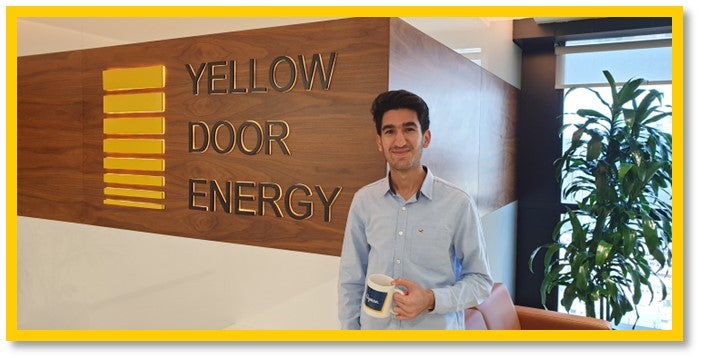Ayman standing beside the Yellow Door Energy sign