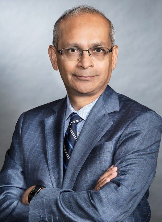 Photo of Waterloo President and Vice Chancellor, Vivek Goel, smiling with his arms crossed