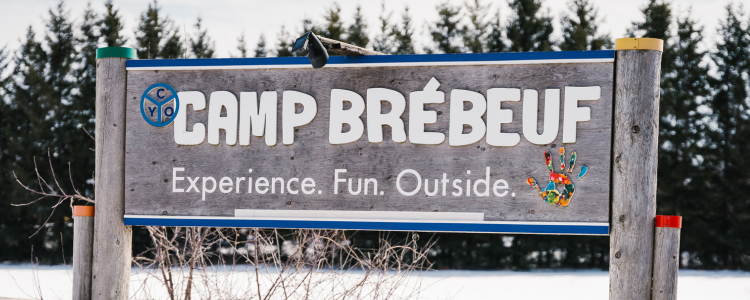 Wooden sign inscribed with 'Camp Brebeuf - Experience.Fun.Outside&quot;