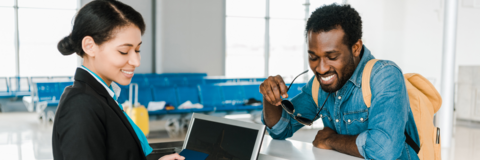 Airport worker smiling and checking in male traveler