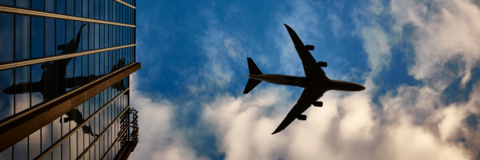 Photo from below of airplane in the sky in downtown area