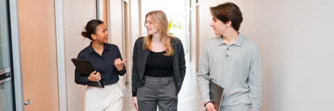 Two co-op students and an employer walking through an office hallway chatting
