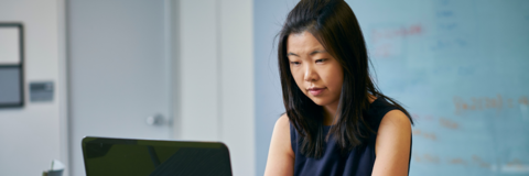 Female student typing on laptop in office