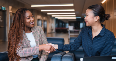 Female employer shaking female students hand in office building