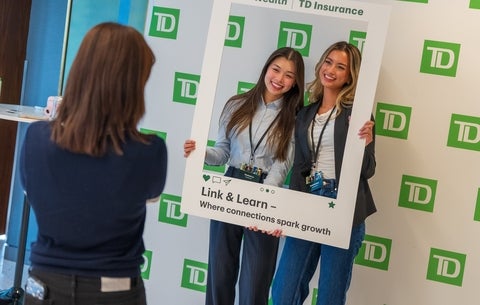 Breanna Levy and a colleague posing in front of a TD backdrop with a frame prop