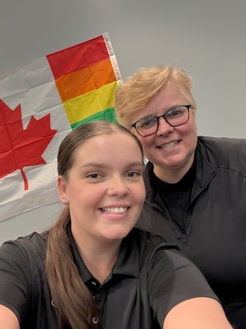 Brooke Driscoll with coworker posing in front of a Canadian pride flag
