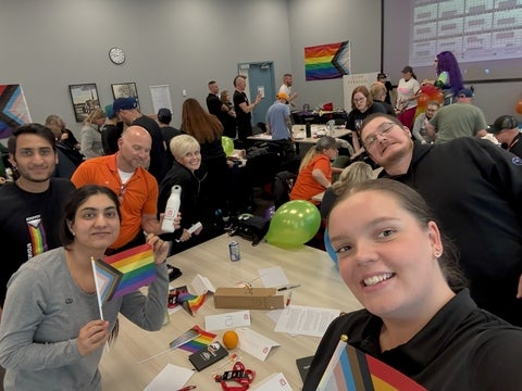 Brooke Driscoll smiling with coworkers and holding pride flags