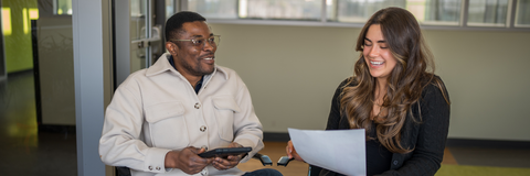 student sitting beside advisor with paper in hand