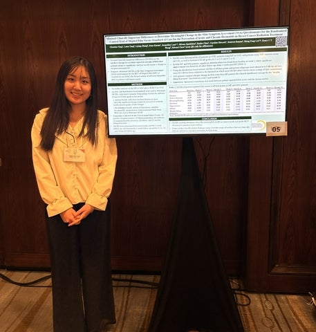 Christina Yang posing in front of a presentation monitor