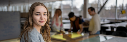 student looking at camera with other students in the background