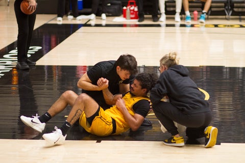 Daniel Proietti assisting hurt athlete on gym floor