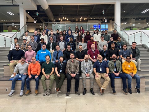 A large group of employees posing together on a staircase inside an office building during a company event or team gathering.
