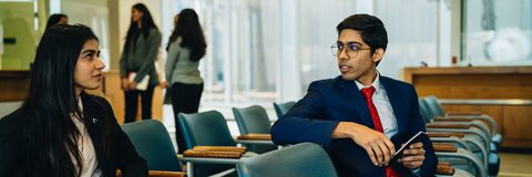 Two students sitting in TC interview waiting area talking to each other 