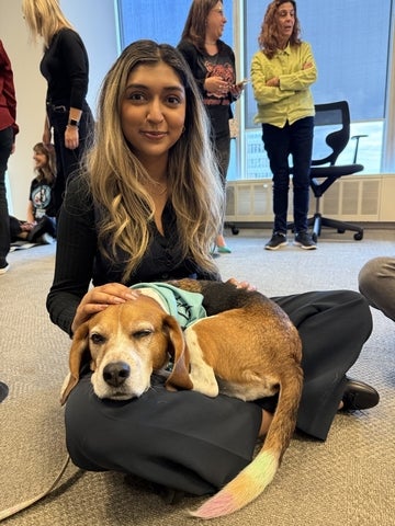 Herra Rodrigo smiling at an office with a dog in her lap.