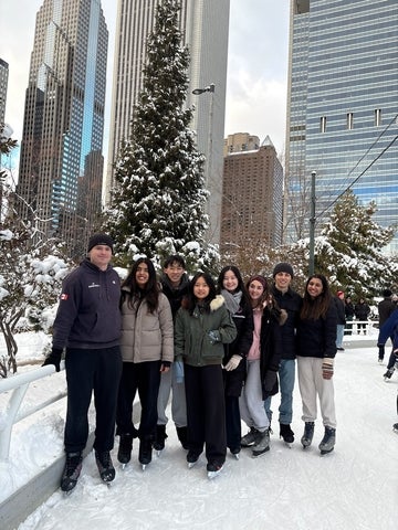 Avni and coworkers standing together outdoors in a snowy city plaza, posing for a photo in front of a pine tree